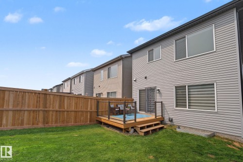 Rear exterior featuring light grey siding and a wooden deck with dark railings - 432 Roberts Crescent, Leduc, AB 