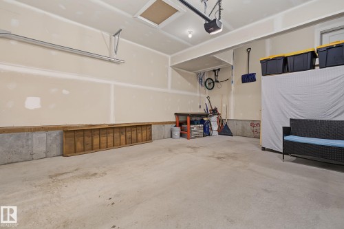 Spacious garage featuring a concrete floor, concrete foundation perimeter, and an automatic garage door opener - 432 Roberts Crescent, Leduc, AB 