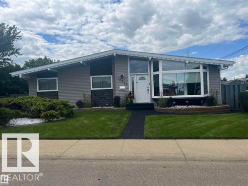 Mid-century modern residence featuring gray siding, a prominent bay window, and a white arched entry door - 13304 70 Street, Edmonton, AB 