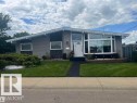Mid-century modern residence featuring gray siding, a prominent bay window, and a white arched entry door - 13304 70 Street, Edmonton, AB 