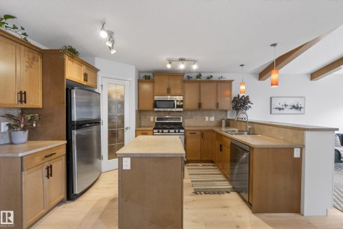 Kitchen featuring light wood-finish cabinetry, stainless steel appliances, an island, and pendant lighting - 2696 Anderson Crescent, Edmonton, AB - Indoor Photo Showing Kitchen With Double Sink