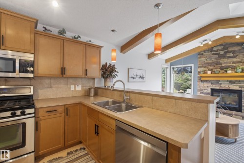 Kitchen featuring stainless steel appliances, light wood cabinetry, and a double basin sink - 2696 Anderson Crescent, Edmonton, AB - Indoor Photo Showing Kitchen With Double Sink