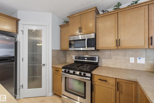 Kitchen featuring stainless steel appliances, light wood cabinetry, and a tile backsplash - 2696 Anderson Crescent, Edmonton, AB - Indoor Photo Showing Kitchen