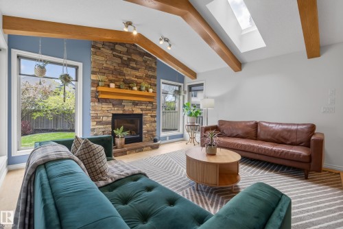 Vaulted ceiling with exposed wood beams and a central skylight - 2696 Anderson Crescent, Edmonton, AB - Indoor Photo Showing Living Room With Fireplace