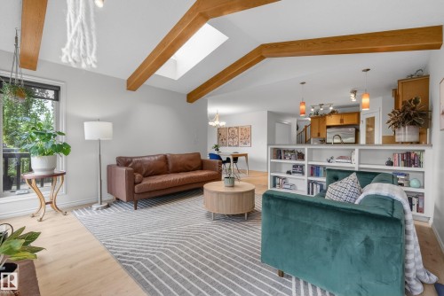 Living area featuring vaulted ceilings with exposed wood beams, a skylight, and wood-finish flooring - 2696 Anderson Crescent, Edmonton, AB - Indoor Photo Showing Living Room