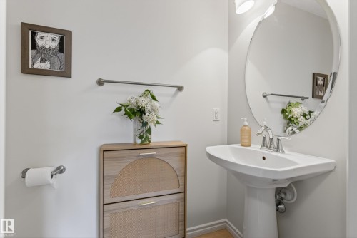 Pedestal sink with chrome faucet, complemented by an oval-shaped mirror with integrated lighting - 2696 Anderson Crescent, Edmonton, AB - Indoor Photo Showing Bathroom