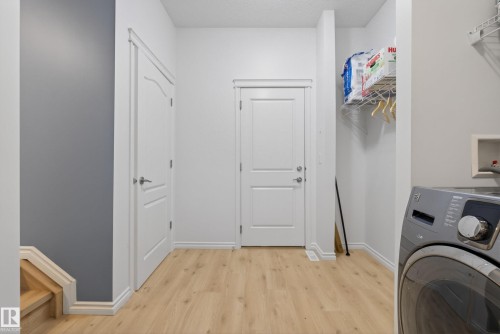 Dedicated laundry area featuring wood-finish flooring, white trim, and a built-in wire shelving unit - 2696 Anderson Crescent, Edmonton, AB - Indoor Photo Showing Laundry Room