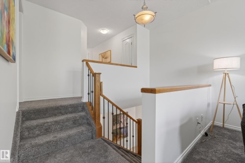 Carpeted staircase with wood-finish handrail and black metal balusters - 2696 Anderson Crescent, Edmonton, AB - Indoor Photo Showing Other Room
