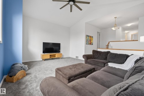 Vaulted ceiling featuring a ceiling fan, carpeted flooring, a partial blue accent wall, and a wood-finish railing - 2696 Anderson Crescent, Edmonton, AB - Indoor Photo Showing Living Room