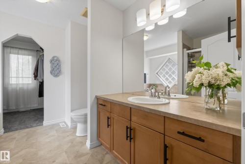 Bathroom vanity featuring a light wood-finish cabinet with matte black hardware, a light-toned countertop, and an integrated oval sink with a chrome faucet - 2696 Anderson Crescent, Edmonton, AB - Indoor Photo Showing Bathroom
