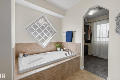 Built-in soaking tub featuring a tiled surround, chrome fixtures, and a decorative glass block window - 2696 Anderson Crescent, Edmonton, AB - Indoor Photo Showing Bathroom