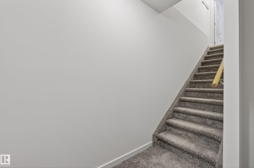 Staircase featuring grey carpeted treads, a light-toned wooden handrail, and white painted walls - 2696 Anderson Crescent, Edmonton, AB - Indoor Photo Showing Other Room
