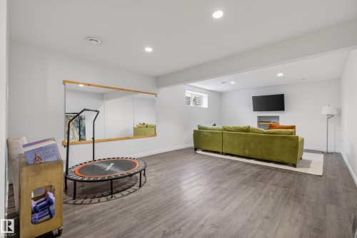 Spacious room featuring wood-finish flooring, recessed lighting, and a mounted television - 2696 Anderson Crescent, Edmonton, AB - Indoor