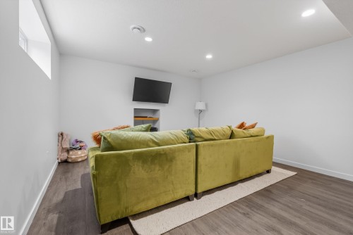 Spacious room featuring wood-finish flooring, recessed ceiling lighting, and a window for natural light - 2696 Anderson Crescent, Edmonton, AB - Indoor With Fireplace