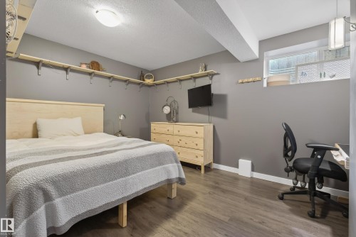 Bedroom featuring wood-finish flooring, a light wood headboard, and a built-in wall shelf system - 2696 Anderson Crescent, Edmonton, AB - Indoor Photo Showing Bedroom