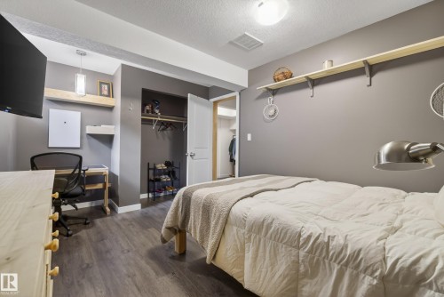 Bedroom featuring wood-finish flooring, a built-in closet with hanging rod and shelving, a ceiling-mounted light fixture, and a wall-mounted display shelf - 2696 Anderson Crescent, Edmonton, AB - Indoor Photo Showing Bedroom