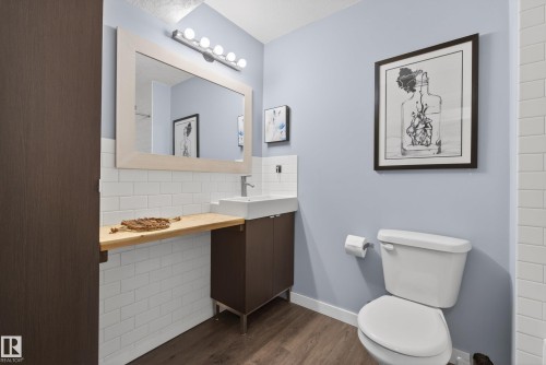 Contemporary bathroom featuring wood-finish flooring, a white subway tile wainscoting, and a floating vanity with a vessel sink - 2696 Anderson Crescent, Edmonton, AB - Indoor Photo Showing Bathroom