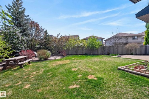 Spacious backyard featuring an expansive lawn, mature trees, privacy fencing, a paver patio area, and a raised garden bed - 2696 Anderson Crescent, Edmonton, AB - Outdoor