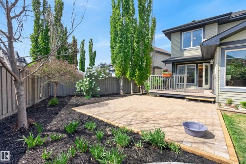 Private backyard featuring a paved patio, a raised wooden deck, mature trees, and landscaping with perennial plantings - 2696 Anderson Crescent, Edmonton, AB - Outdoor With Deck Patio Veranda