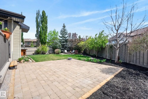 Spacious backyard with a paved patio area, manicured lawn, and mature trees - 2696 Anderson Crescent, Edmonton, AB - Outdoor