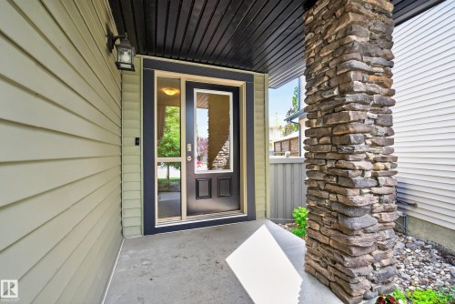 Entryway featuring a stone-clad column, concrete porch, and a black front door with glass panels - 2696 Anderson Crescent, Edmonton, AB - Outdoor With Exterior