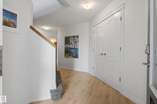 Entryway featuring wood-finish flooring, white trim, and a staircase with a wood handrail and carpeted lower section - 2696 Anderson Crescent, Edmonton, AB - Indoor Photo Showing Other Room