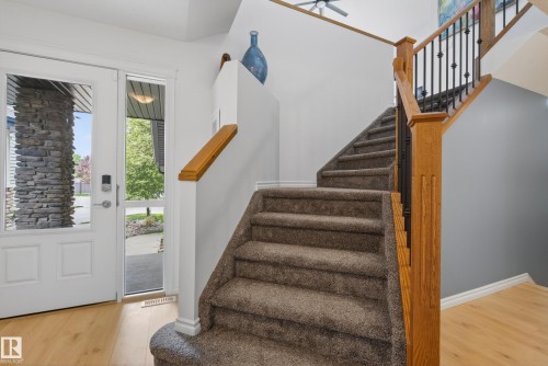 Inviting entry featuring wood-finish flooring and a carpeted staircase with wood newel posts and wrought iron balusters - 2696 Anderson Crescent, Edmonton, AB - Indoor Photo Showing Other Room