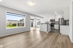 Spacious interior featuring wood-finish flooring, light grey walls, and a large window overlooking the backyard - 