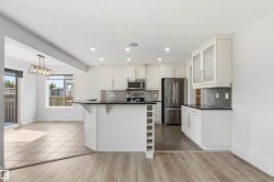 Modern kitchen featuring white cabinetry, stainless steel appliances, dark countertops, and a patterned tile backsplash - 