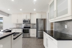 Modern kitchen featuring white cabinetry, dark countertops, and stainless steel appliances - 