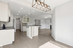 Kitchen featuring white cabinetry, black countertops, stainless steel appliances, and a tiled backsplash - 
