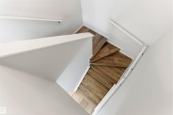 Spiral staircase featuring wood-finish treads, white risers, and white handrails - 