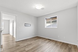 Light-filled room featuring wood-finish flooring, a white trim package, and a flush-mount ceiling light - 