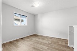 Room featuring wood-finish flooring, light grey walls, and white trim - 