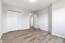 Room featuring light gray walls, wood-finish flooring, white trim, and a white bi-fold closet door - 