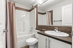 Bathroom featuring a shower-tub combination, ceramic tile surround, vanity with an integrated sink, and a large wall-mounted mirror - 
