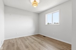 Room featuring wood-finish flooring, a white trim package, and a window providing natural illumination - 