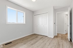 Neutral-toned interior featuring wood-finish flooring, a double window with white trim, and a bi-fold closet with white paneled doors - 