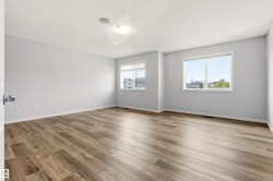 Spacious room featuring light-toned walls and wood-finish flooring - 