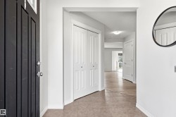 Entryway featuring a dark paneled door with glass inserts, neutral tile flooring, and white bi-fold closet doors - 