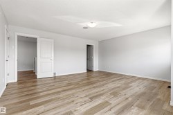 Spacious room featuring wood-finish flooring, light neutral wall paint, and white trim - 
