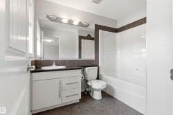 Full bathroom featuring a white vanity with integrated sink, dark countertop, and tiled backsplash - 