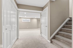 Finished lower level featuring neutral carpeting, recessed lighting, white interior doors, a window, and a carpeted staircase with white trim - 