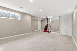 Finished lower level with neutral carpeting, recessed lighting, and egress windows - 