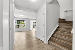 Entryway featuring wood-finish flooring, a staircase with wood-finish treads, a white paneled door, and neutral wall tones - 