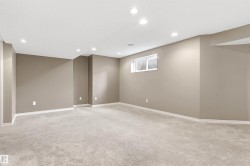 Spacious room featuring light gray carpeting, recessed ceiling lighting, a single window, and neutral-toned walls with white baseboards - 