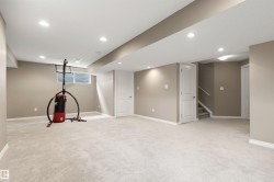 Spacious interior room featuring light-colored carpeting, neutral wall tones, white trim, recessed lighting, and a visible window - 