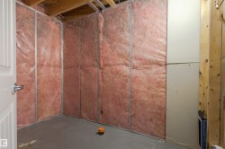 Unfinished interior space featuring exposed insulation, metal framing, drywall sections, and a concrete floor - 