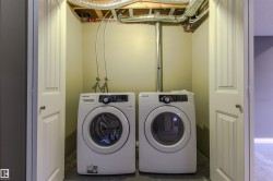 Dedicated laundry alcove featuring a front-loading washer and dryer, finished with neutral-toned walls and a concrete floor - 