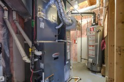 Dedicated utility space featuring a Lennox furnace, an attached water heater, extensive ductwork, and exposed insulation - 